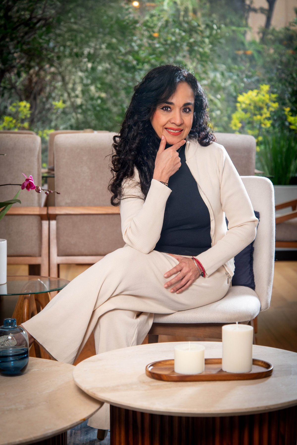 Sandy Casal, sentada en un sillón beige de un salón moderno con un blazer crema y expresión cercana y reflexiva